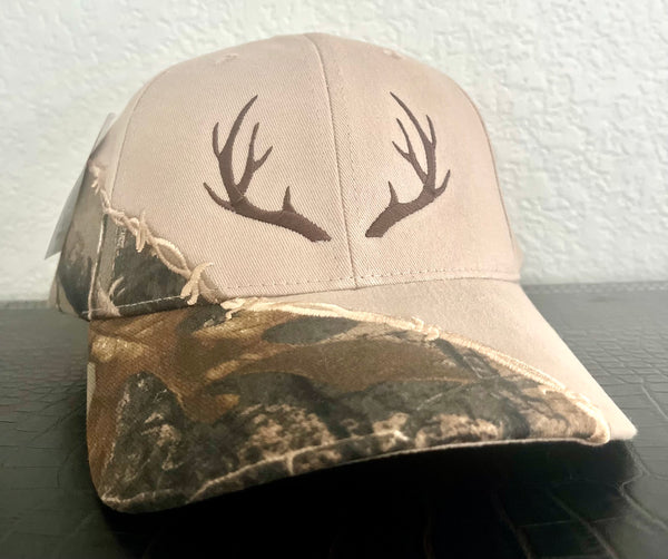 Camouflage baseball cap with deer antlers on a dark surface