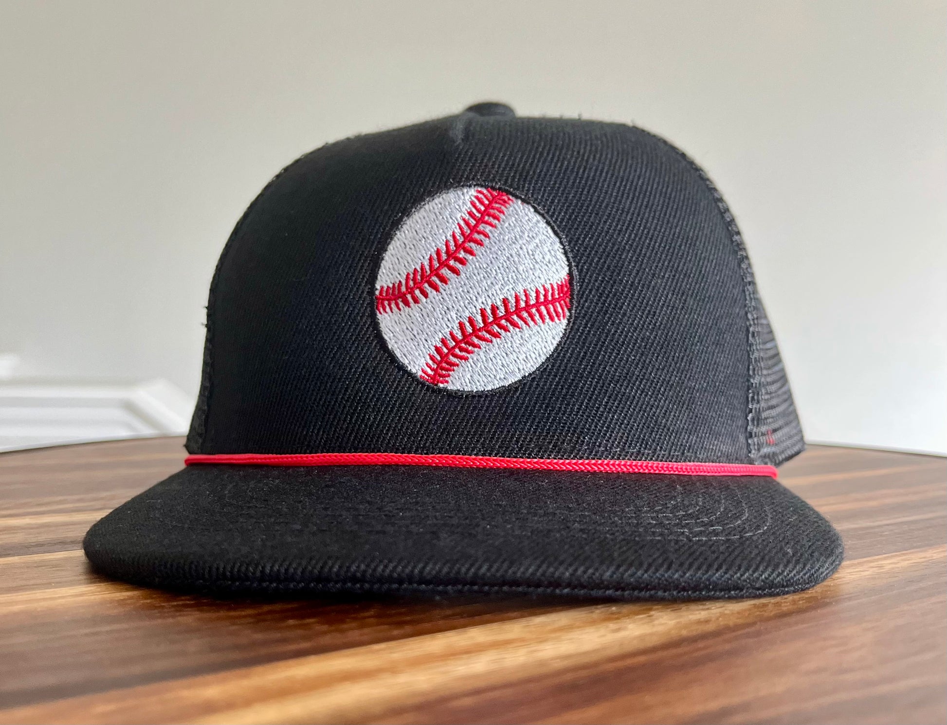 Black cap with a baseball design on a wooden surface