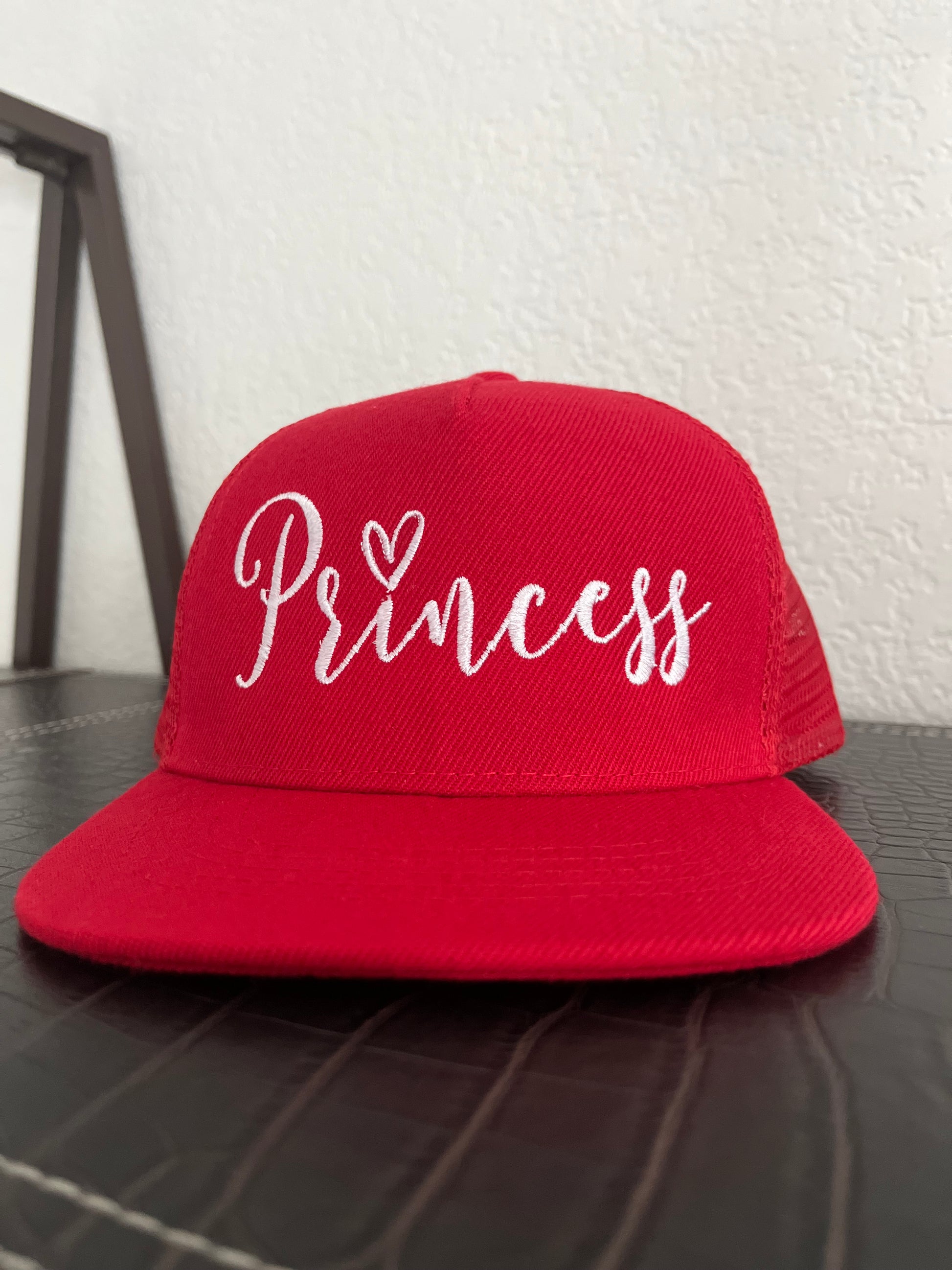 Red cap with 'Princess' text on a textured surface