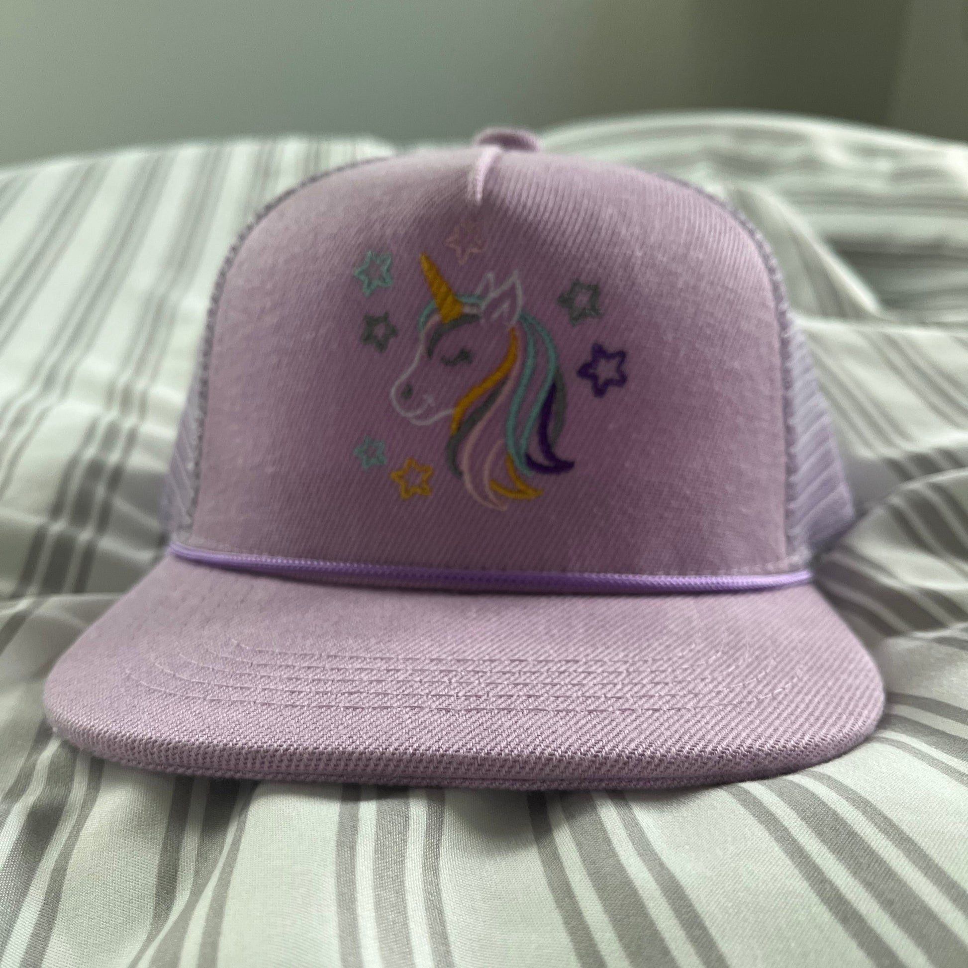 Purple pillow with unicorn design on a striped fabric background