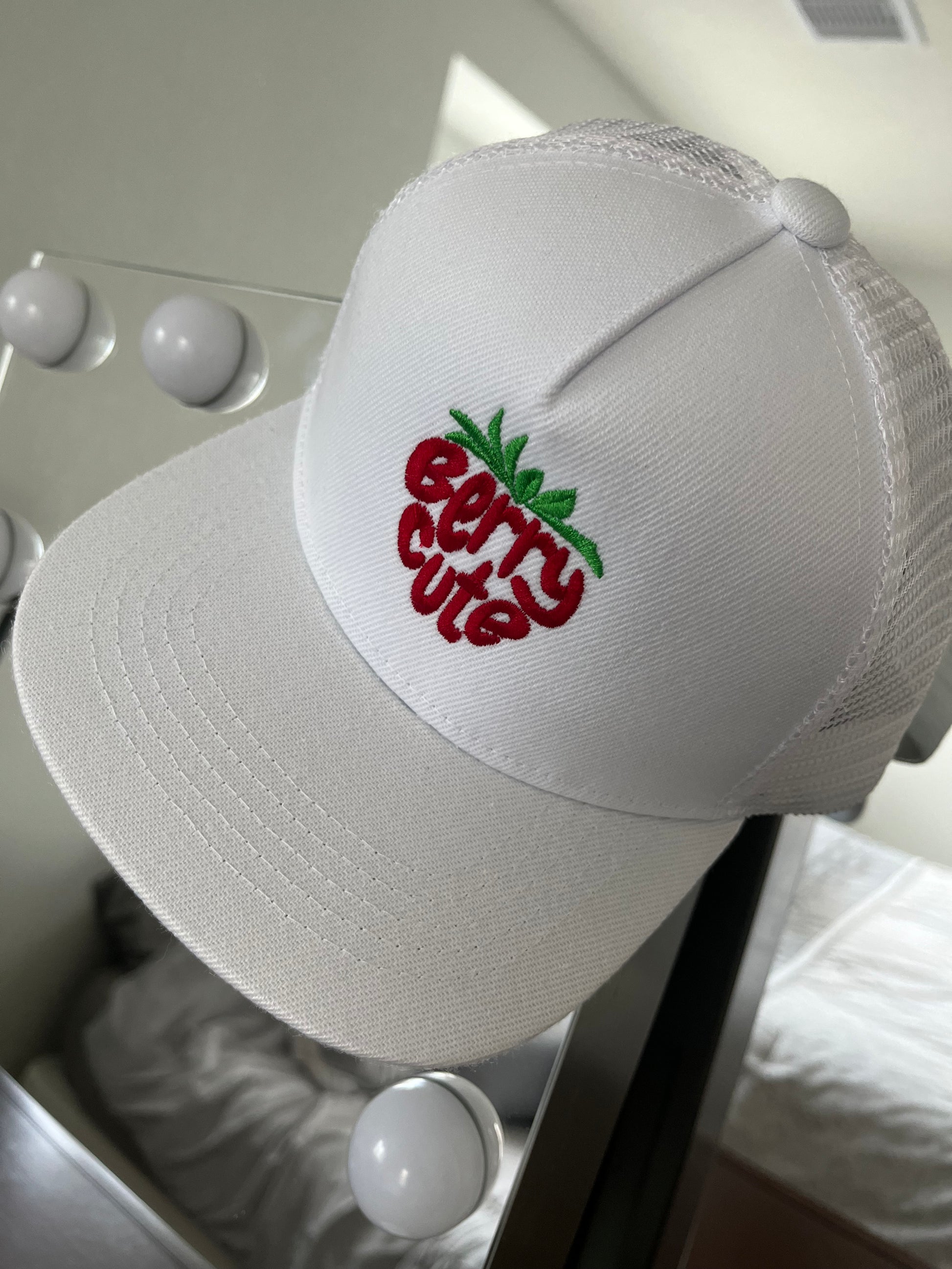 White cap with 'Berry Cute' embroidery on a white background