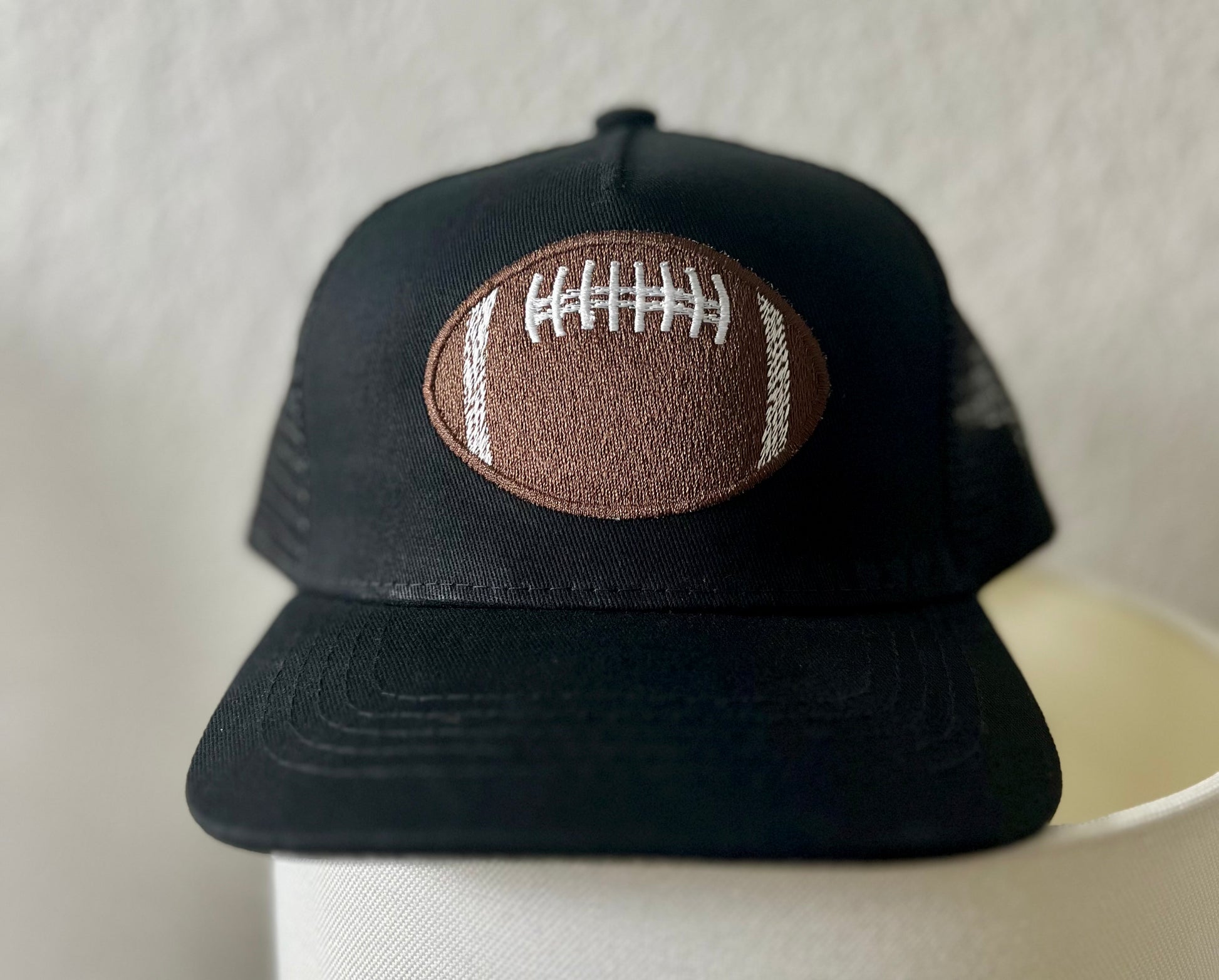 Black cap with a football patch on a white surface