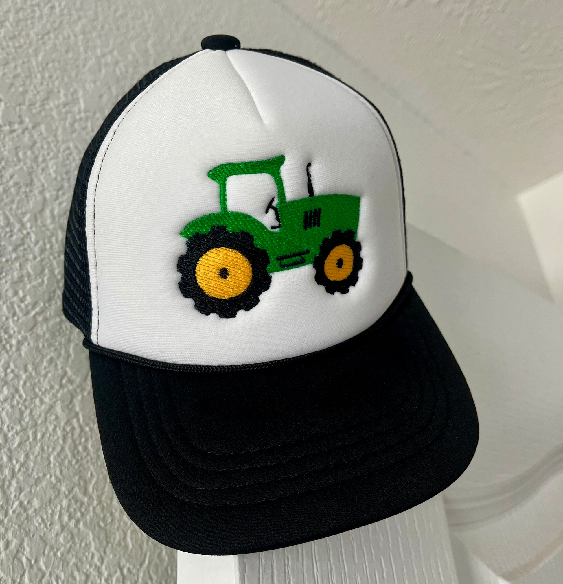 Trucker hat with a green tractor design on a white background