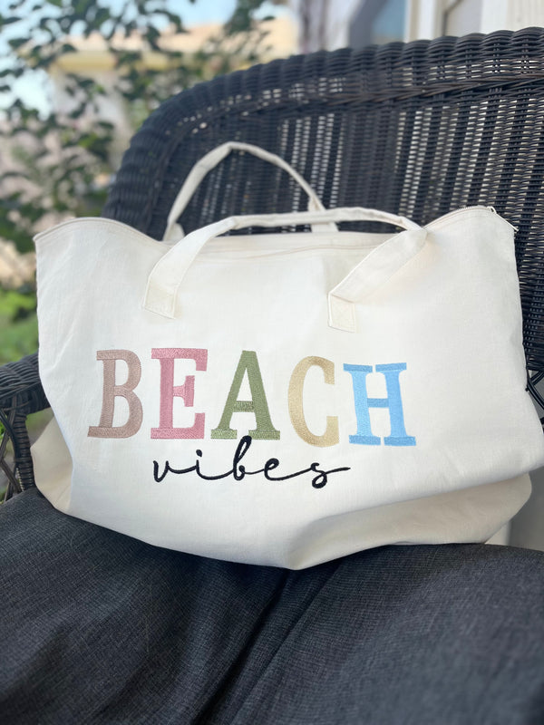 White tote bag with 'BEACH vibes' text on a wicker chair outdoors