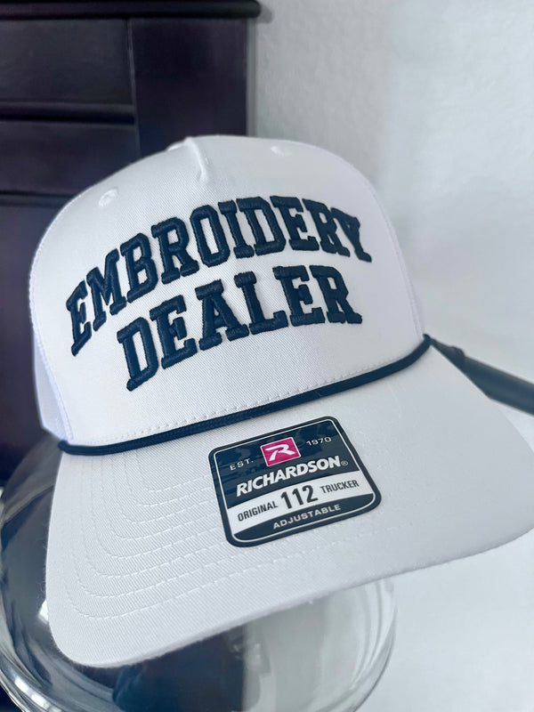 White cap with 'Embroidery Dealer' text and Richardson logo on a reflective surface.