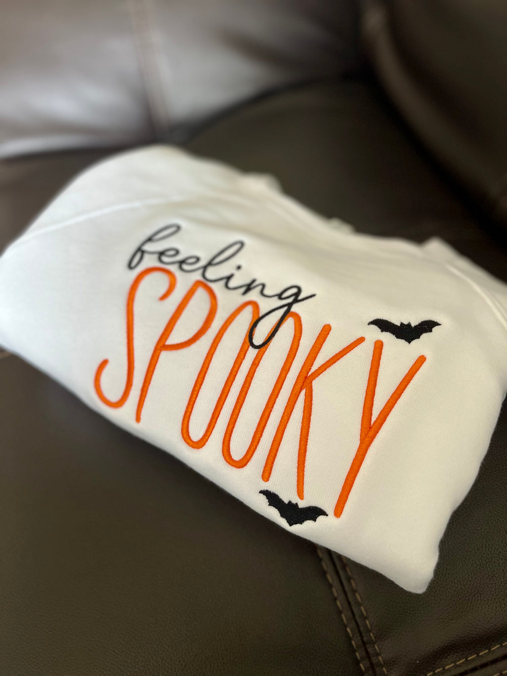 Folded white blanket with 'feeling spooky' text and bats on a brown surface