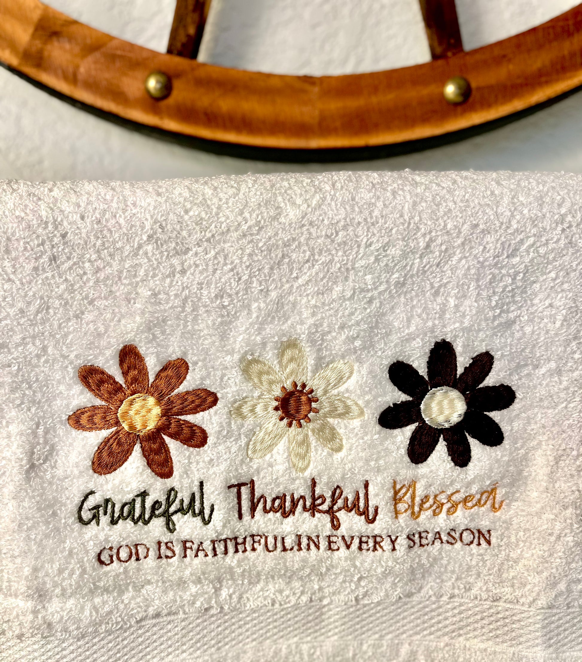 Towel with embroidered flowers and text on a wooden surface