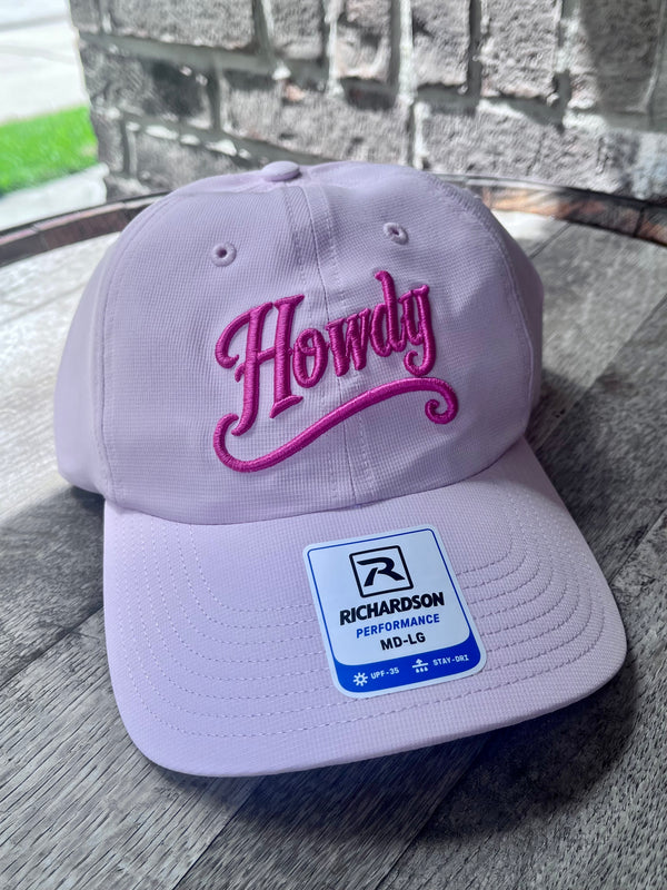 Light purple cap with 'Howdy' in pink on a wooden surface