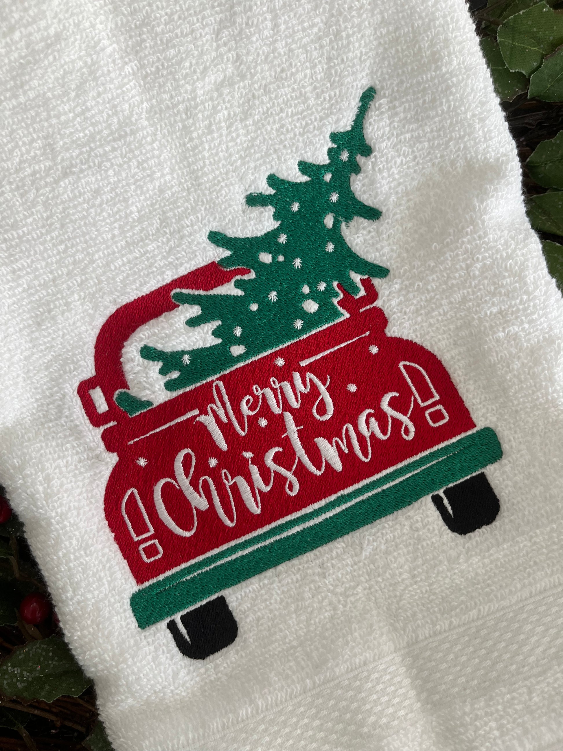 White towel with a red and green Christmas-themed design featuring a tree and text.
