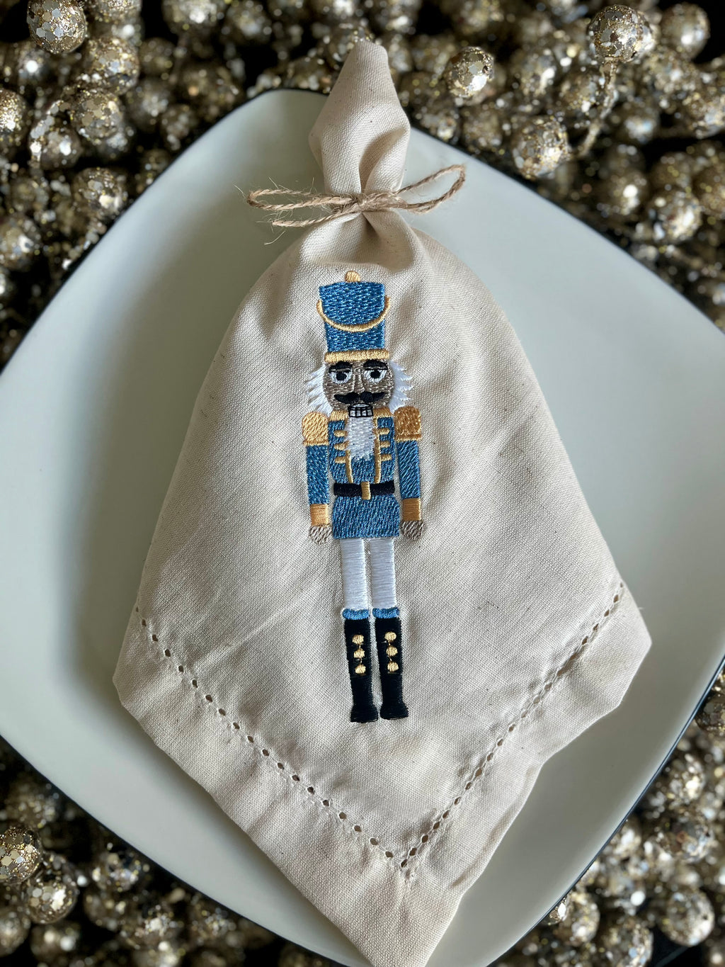Napkin with embroidered nutcracker design on a decorative plate.