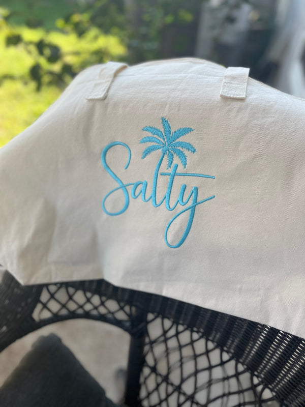 White shirt with 'Salty' and palm tree design on a blurred background