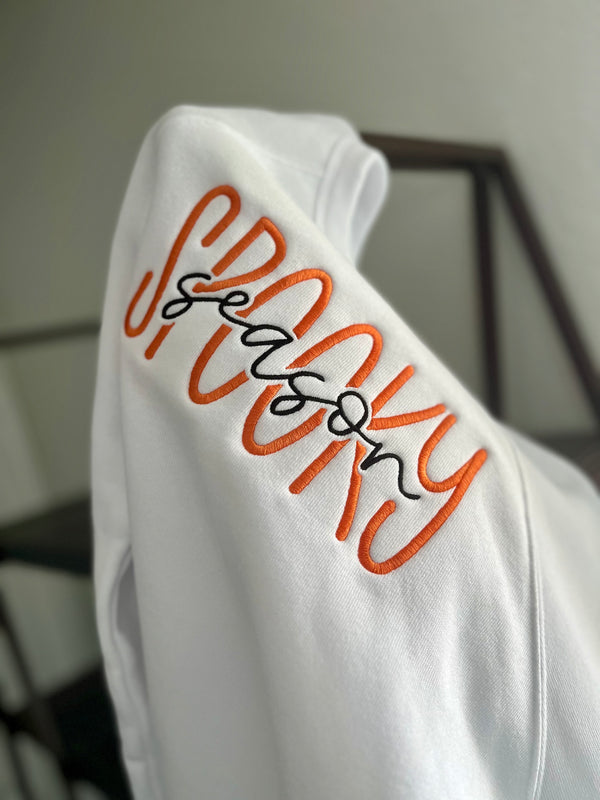 White sweatshirt with orange and black text on a plain background