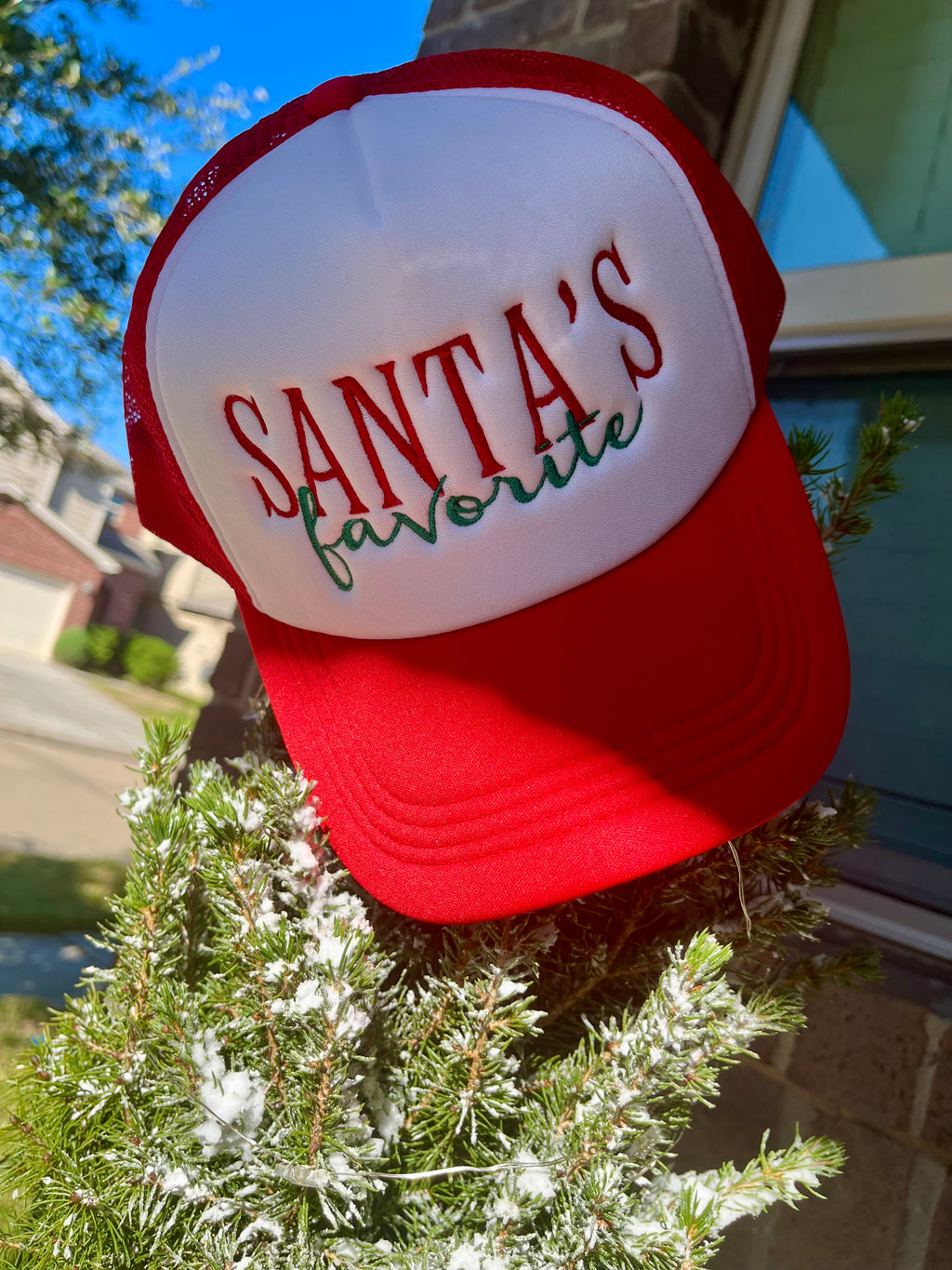 Red and white cap with 'Santa's favorite' text on a Christmas tree.